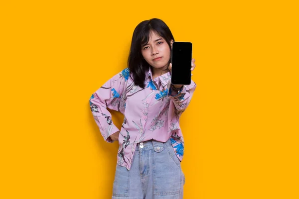 Young Beautiful Asian Woman Demonstrating Mobile Cell Phone Isolated Yellow — ストック写真