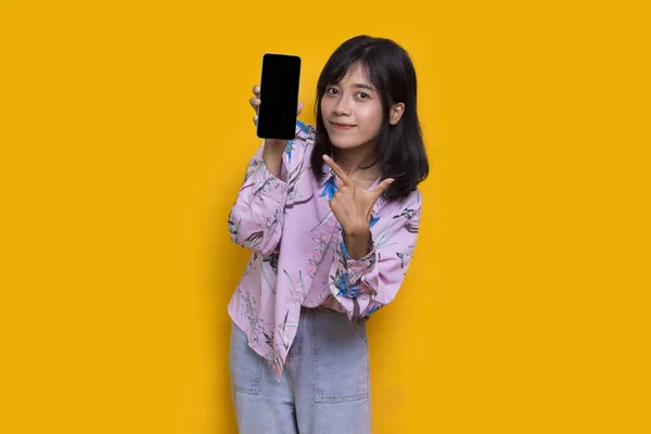 Young Beautiful Asian Woman Demonstrating Mobile Cell Phone Isolated Yellow — Stock Photo, Image