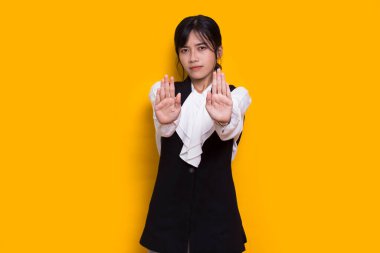 Eli açık genç bir kadın dur işareti yapıyor. Savunma jesti sarı arka planda.