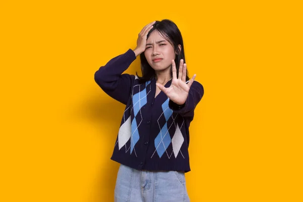 young woman with open hand doing stop sign with serious expression defense gesture isolated on yellow background