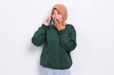 Beyaz arka planda izole edilmiş cep telefonu kullanan Asyalı genç ve üzgün bir müslüman kadın.