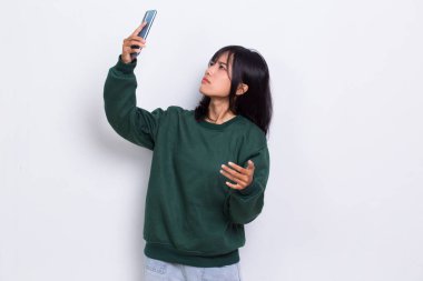 kızgın ve şok olmuş genç Asyalı güzel kadın beyaz arka planda izole cep telefonu kullanıyor.