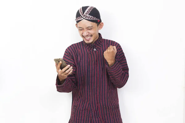 Happy Joyful Asian Man Javanese Traditional Cloth Lurik Using Mobile — Foto de Stock