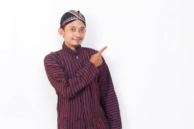 asian man with javanese traditional cloth lurik pointing with fingers to different directions isolated on white background