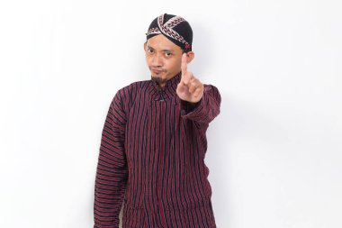 asian man with javanese traditional cloth lurik with open hand doing stop sign with serious expression defense gesture isolated on white background
