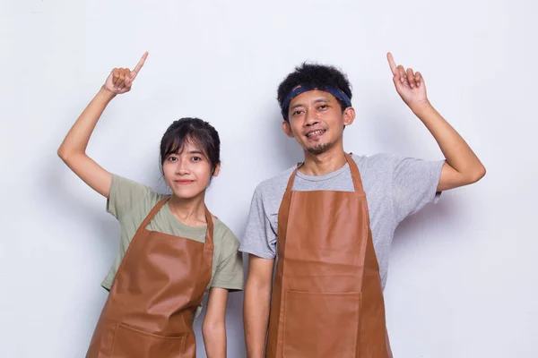 Asian couple barista waiter wears apron pointing with fingers to different directions isolated on white background