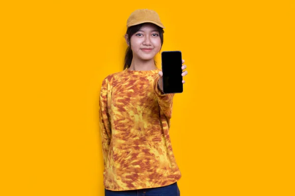 Sarı Arka Planda Cep Telefonu Gösterisi Yapan Genç Güzel Asyalı — Stok fotoğraf