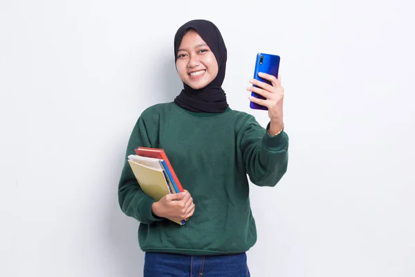 美しいアジアのビジネスムスリム女性は白い背景に隔離された携帯電話を使って本を抱いています — ストック写真