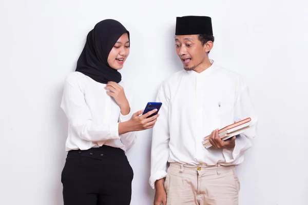 Молода Азіатська Мусульманська Пара Обіймає Книгу Допомогою Мобільного Телефону Ізольовано — стокове фото