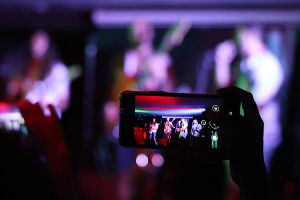 Person recording a concert with a mobile phone