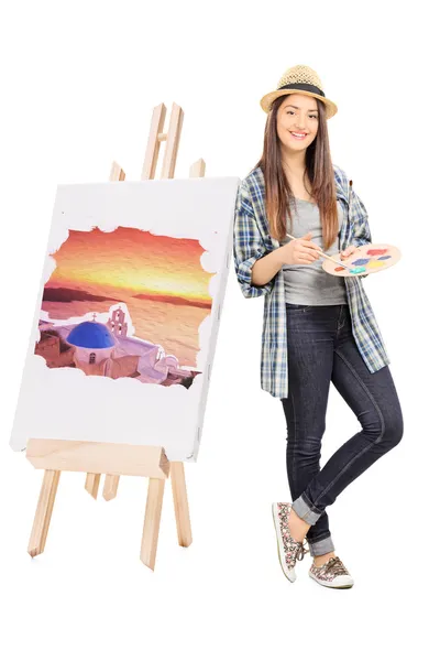 Female artist leaning on an easel with painting — Stock Photo, Image