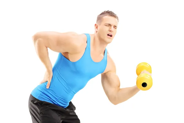 Athlete with back pain lifting a dumbbell — Stock Photo, Image