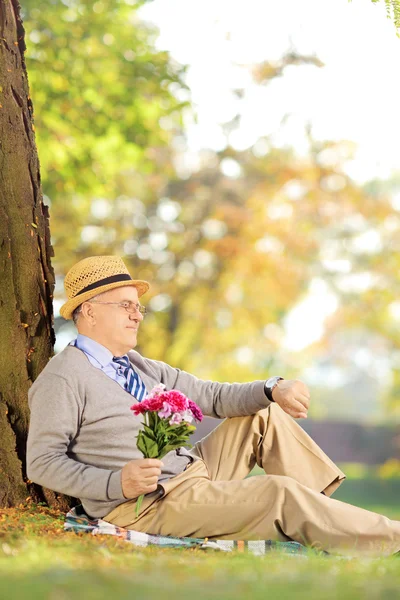 Senior med blommor kontrollera tid — Stockfoto