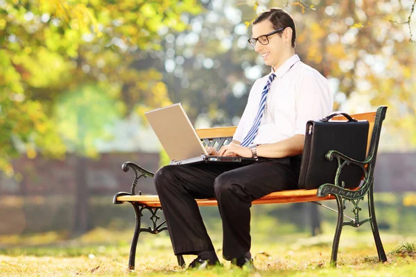 Geschäftsmann sitzt auf Bank und arbeitet am Laptop — Stockfoto