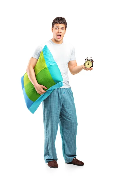 Shocked male holding pillow and clock — Stock Photo, Image