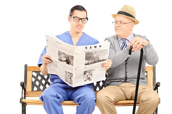 Krankenschwester liest einem älteren Herrn Zeitung — Stockfoto