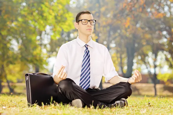 Businessman meditating in a park — Stock Photo, Image