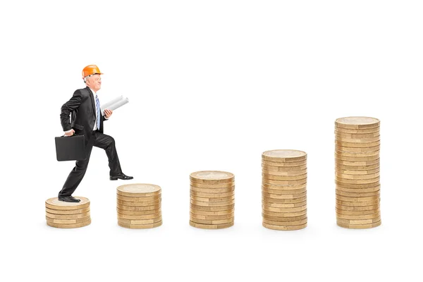 Engineer walking over piles of coins — Stock Photo, Image