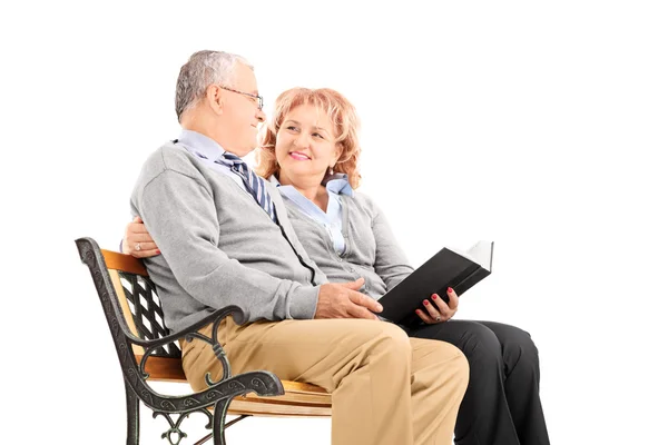 Starsza para na ławce czytając książkę — Zdjęcie stockowe