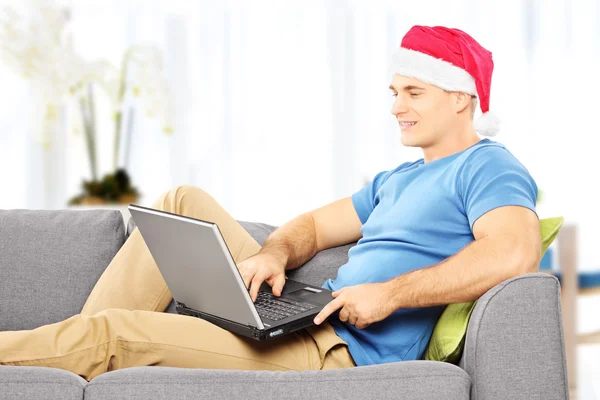 Chico con sombrero de santa trabajando en aaptop — Foto de Stock