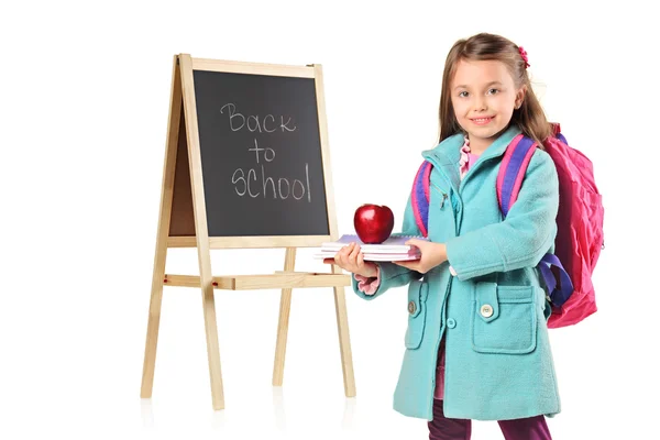 Un niño al lado de una junta escolar sosteniendo libros y manzana roja —  Fotos de Stock