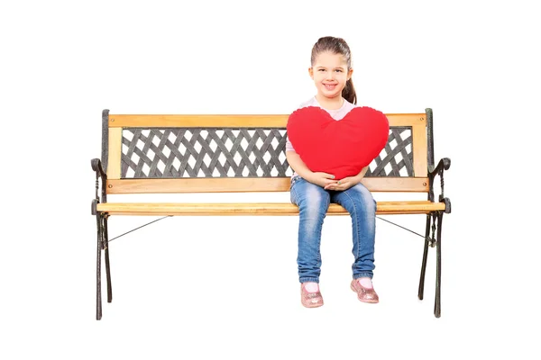 Girl seated on bench holding heart — Stock Photo, Image