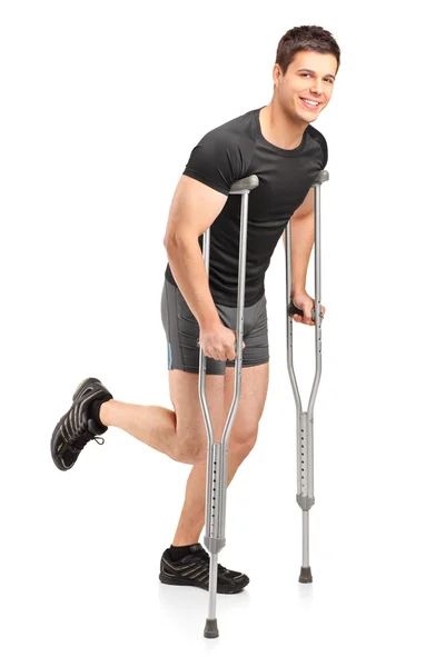 Male athlete walking with crutches — Stock Photo, Image