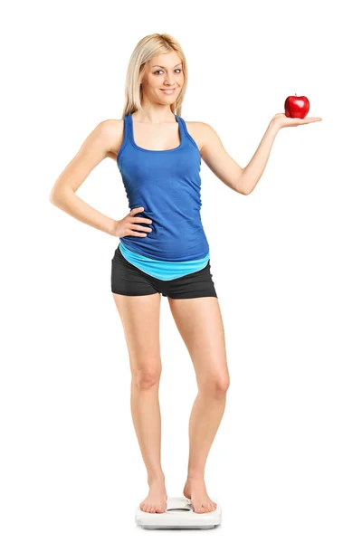 Woman holding apple on weight scale — Stock Photo, Image