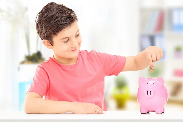 Boy inserting coins into piggybank — Stock Photo, Image