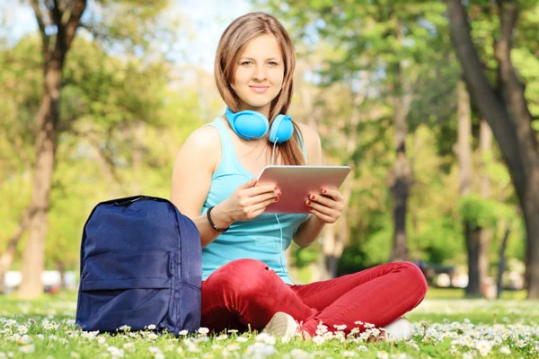 Vrouwelijke student met hoofdtelefoons en Tablet PC — Stockfoto