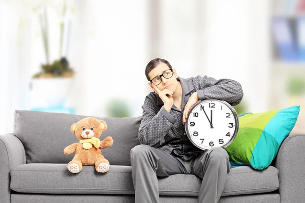 Man in pajamas holding a clock — Stock Photo, Image