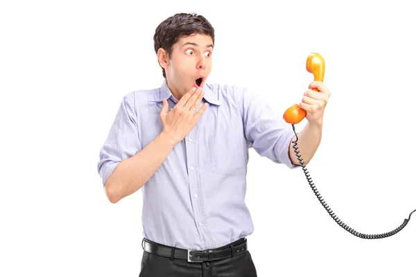 Hombre sorprendido sosteniendo tubo telefónico — Foto de Stock