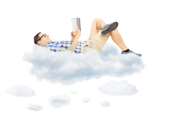 Young male reading a novel and lying on clouds — Stock Photo, Image