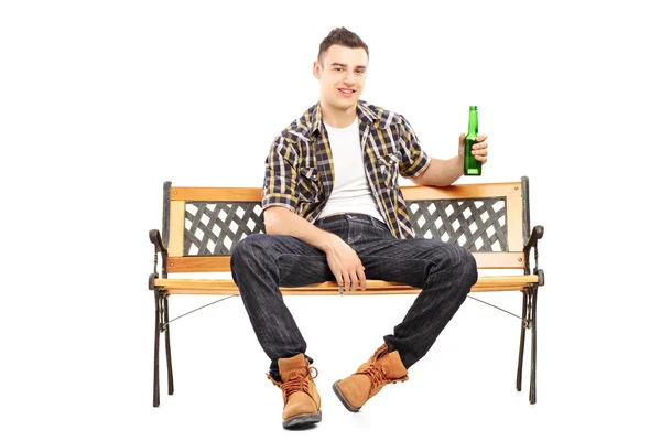 Człowiek na ławce trzymając butelkę piwa — Zdjęcie stockowe