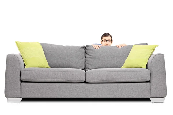 Homem assustado escondido atrás do sofá — Fotografia de Stock