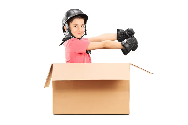 Speelse jongen met helm zitten in kartonnen doos — Stockfoto