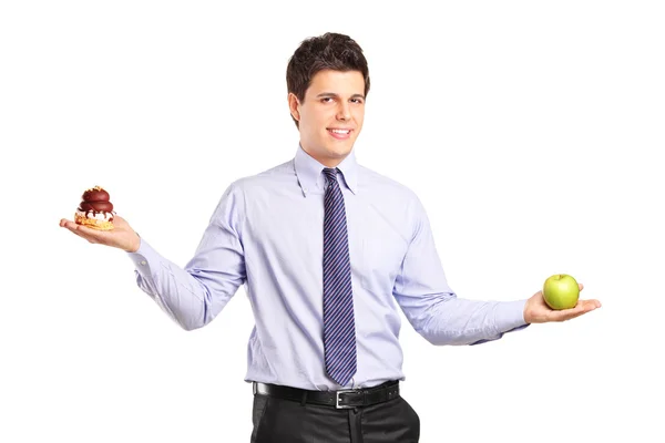 Man holding an apple and cake — Stock Photo, Image