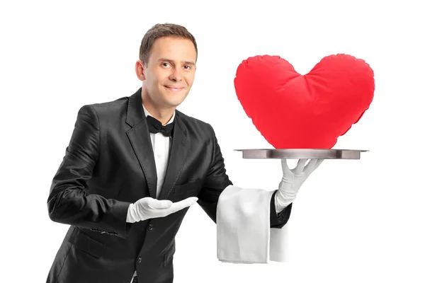 Butler tenant un plateau avec un objet en forme de coeur rouge dessus — Photo