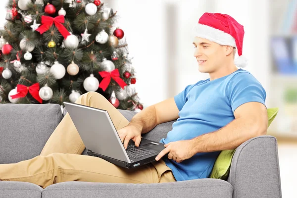 Man with santa hat working on laptop Stock Picture