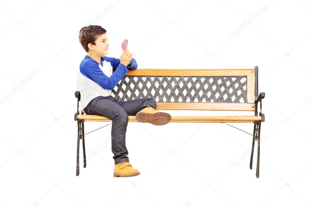 Boy on bench playing cards