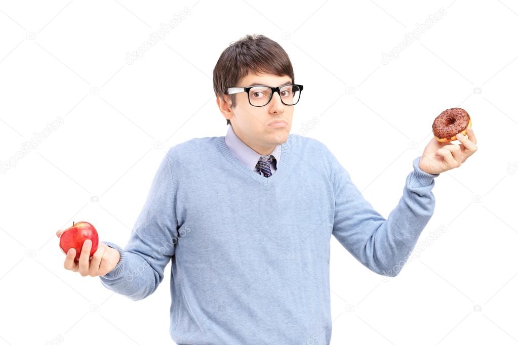 Doubtful guy holding an apple and donut