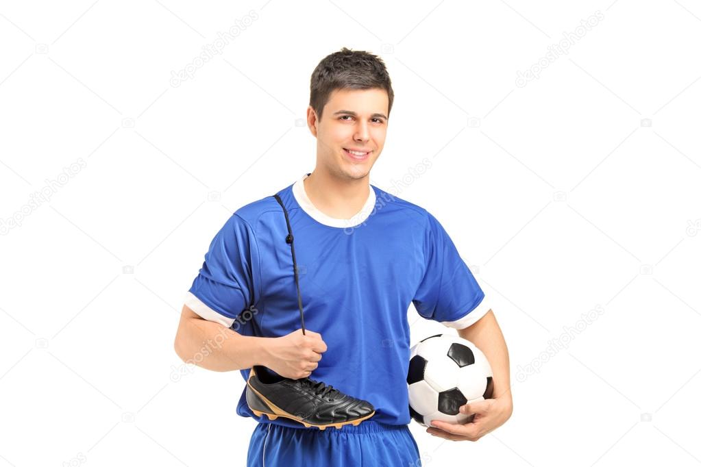 Footballer holding shoes and football