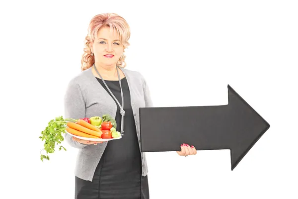 Mulher segurando prato de legumes e flecha — Fotografia de Stock