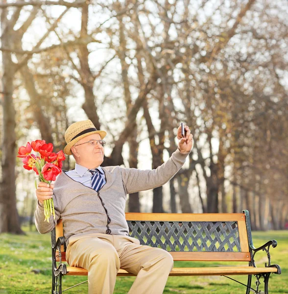 Senior sosteniendo flores y tomando selfie —  Fotos de Stock