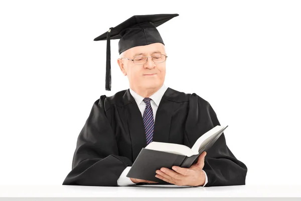 Man met afstuderen hoed lezen van boek — Stockfoto