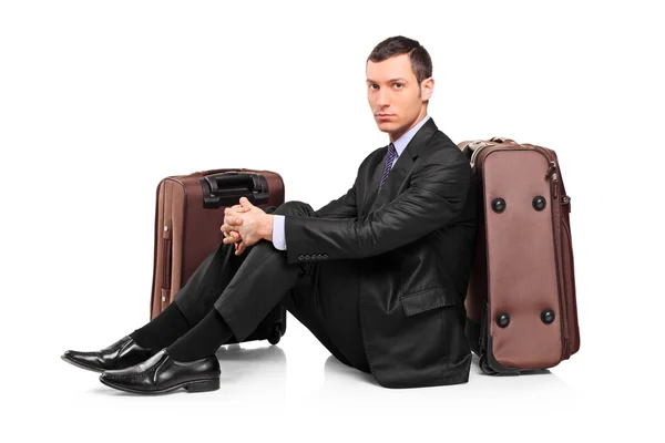 スーツケースの隣に座って待っているビジネス旅行者 — ストック写真