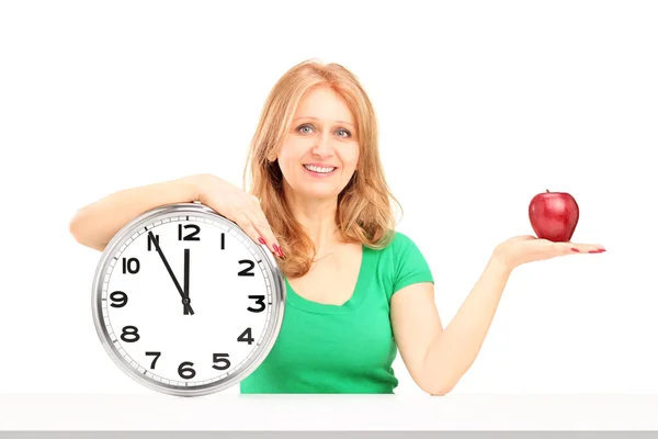 Kobieta gospodarstwa zegar i jabłko — Zdjęcie stockowe
