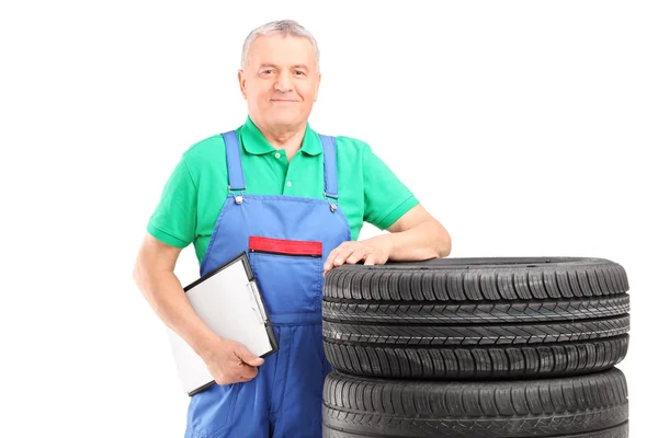 Trabajador maduro posando sobre neumáticos de coche — Foto de Stock