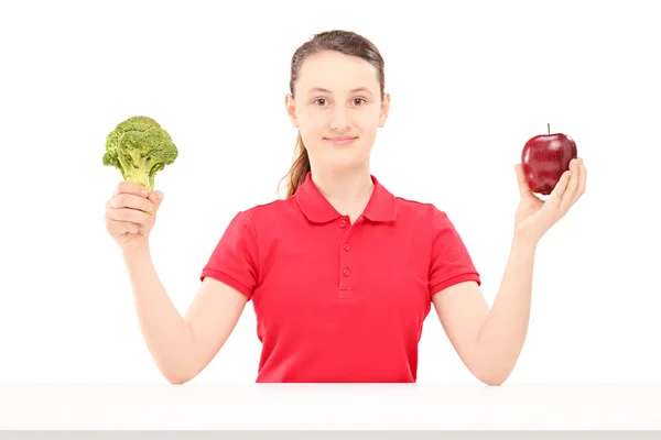 Adolescente sosteniendo manzana y brócoli —  Fotos de Stock
