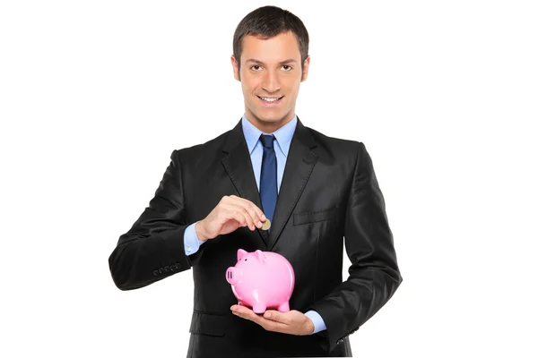 Empresário colocando uma moeda em um banco porquinho — Fotografia de Stock